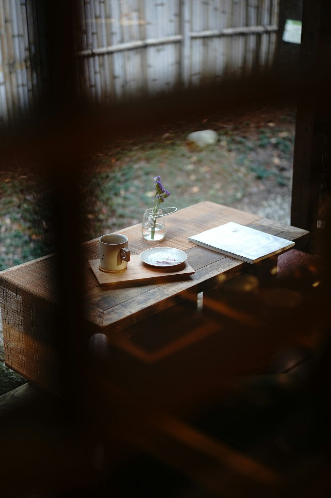 Wooden desk with open notebooks and a ceramic cup in soft window light